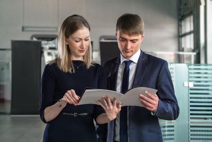 young business man and woman impressed by printed brochure