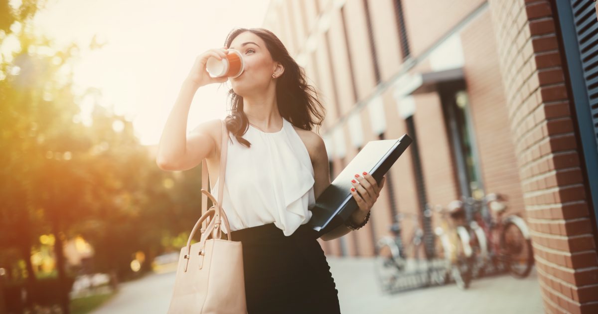 busy businesswoman juggling a coffee with her tablet computer